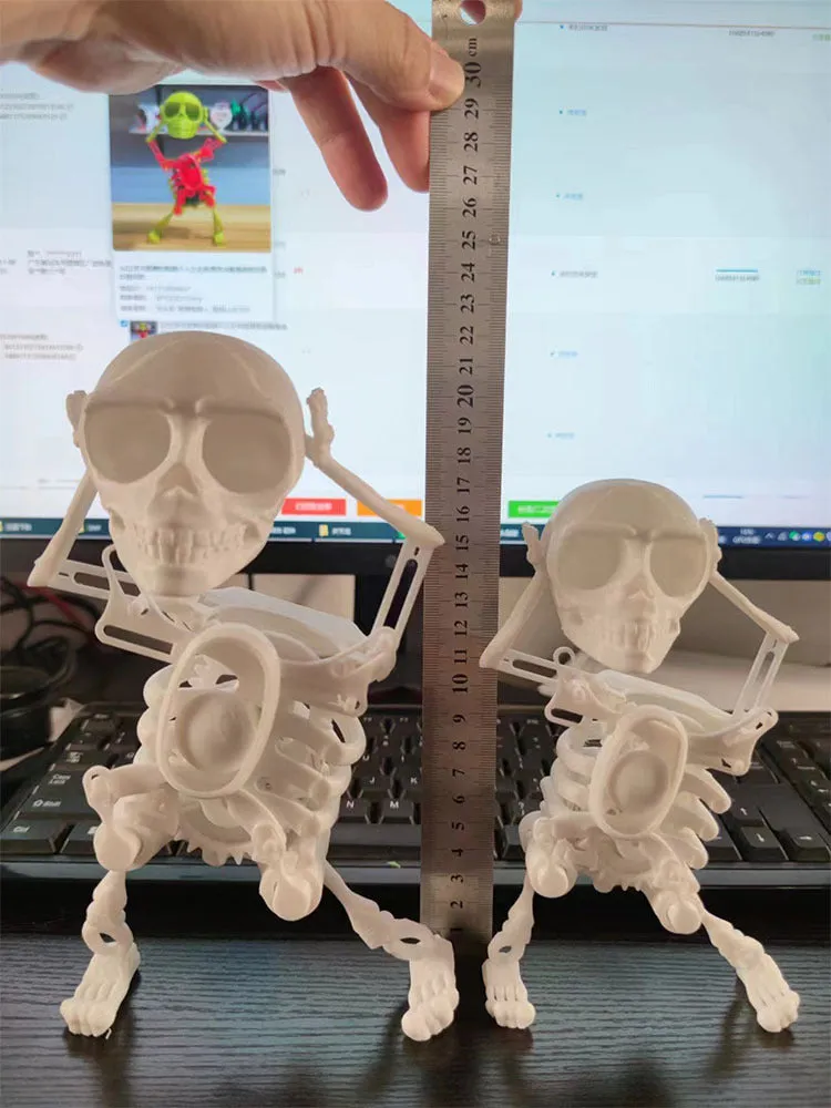 3D printed dancing skeleton gravity toy in pink and white, 22cm tall, on a desk