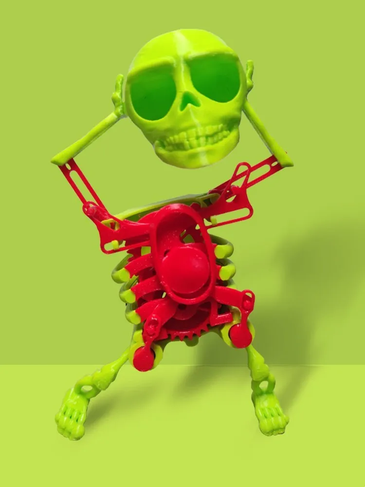 3D printed dancing skeleton gravity toy in pink and white, 22cm tall, on a desk