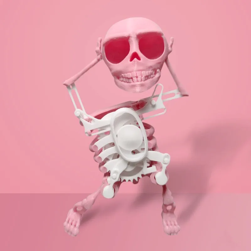 3D printed dancing skeleton gravity toy in pink and white, 22cm tall, on a desk