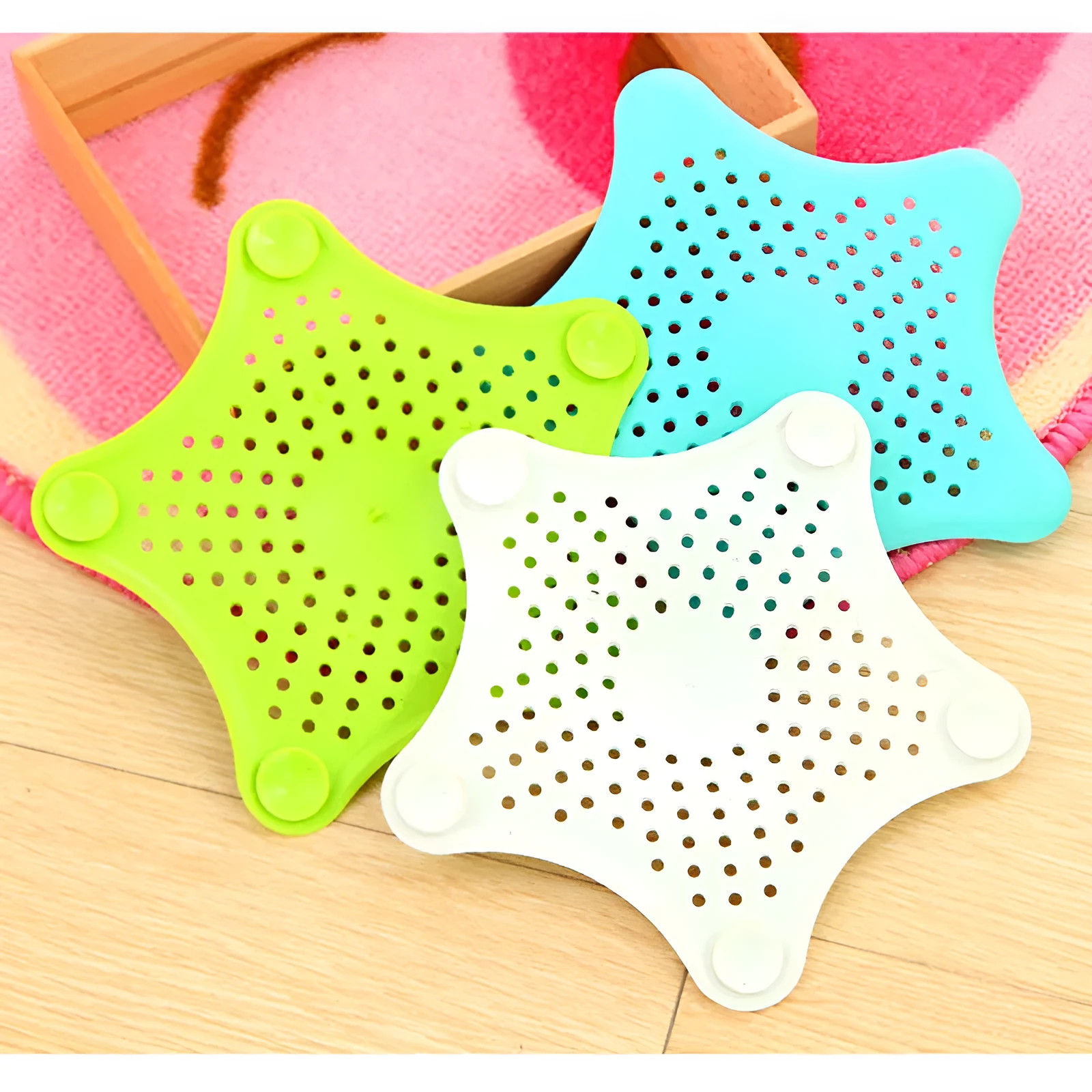 Three silicone starfish sink drain strainers in white, blue, and green with suction cups on bottom