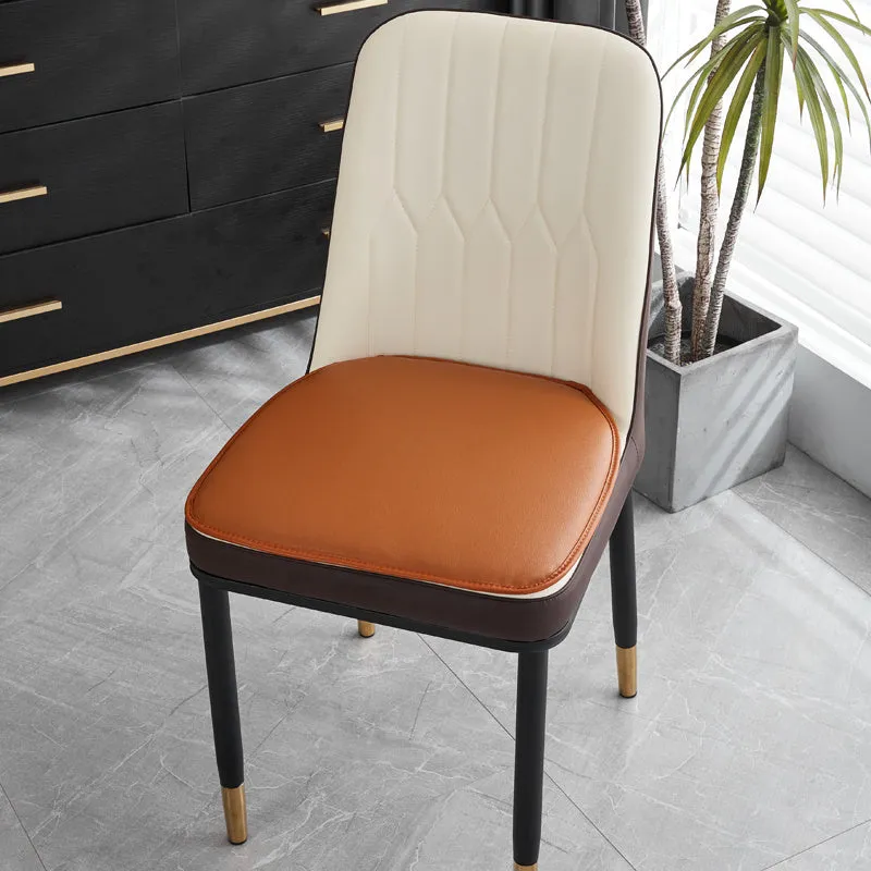 Orange leather horseshoe-shaped seat cushion on a wooden dining chair.