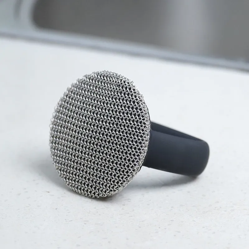 Round 316 stainless steel chainmail scrubber with red silicone handle on cast iron skillet