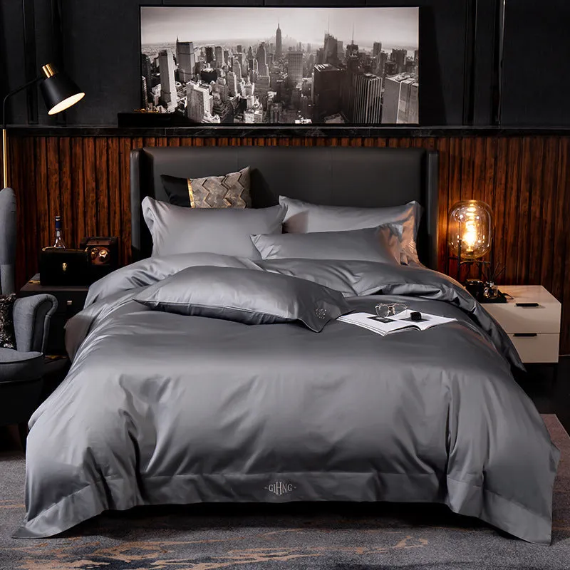 Four-piece cotton satin quilted bedding set with duvet cover, sheet, and pillowcases in a bedroom setting