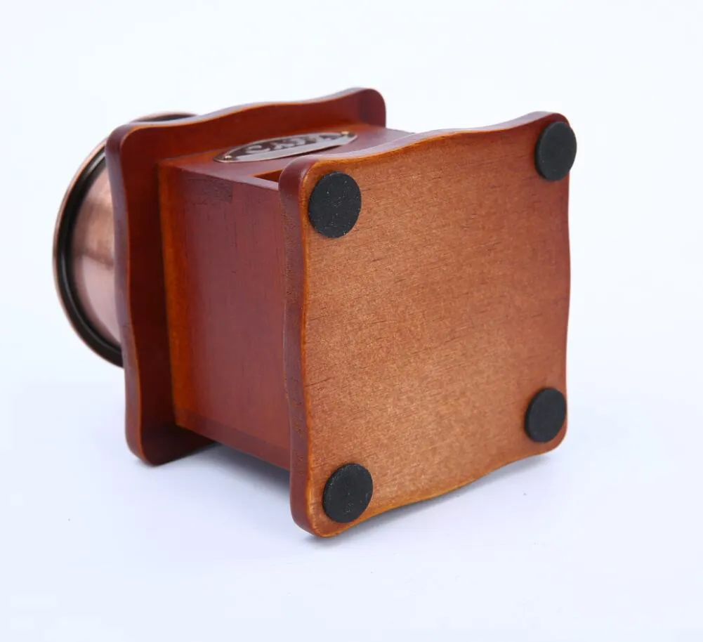 Red manual coffee grinder with ceramic burr and cast iron handle, 10x10x17cm, on a wooden surface