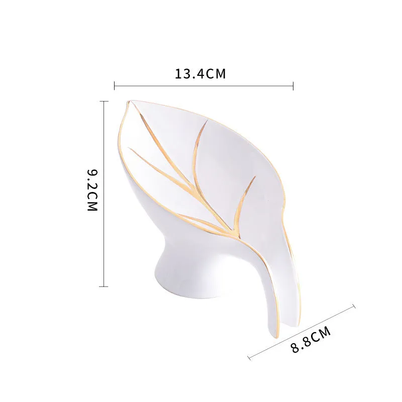 Ceramic leaf shape soap dish with drainage holes and suction cup in white on bathroom counter