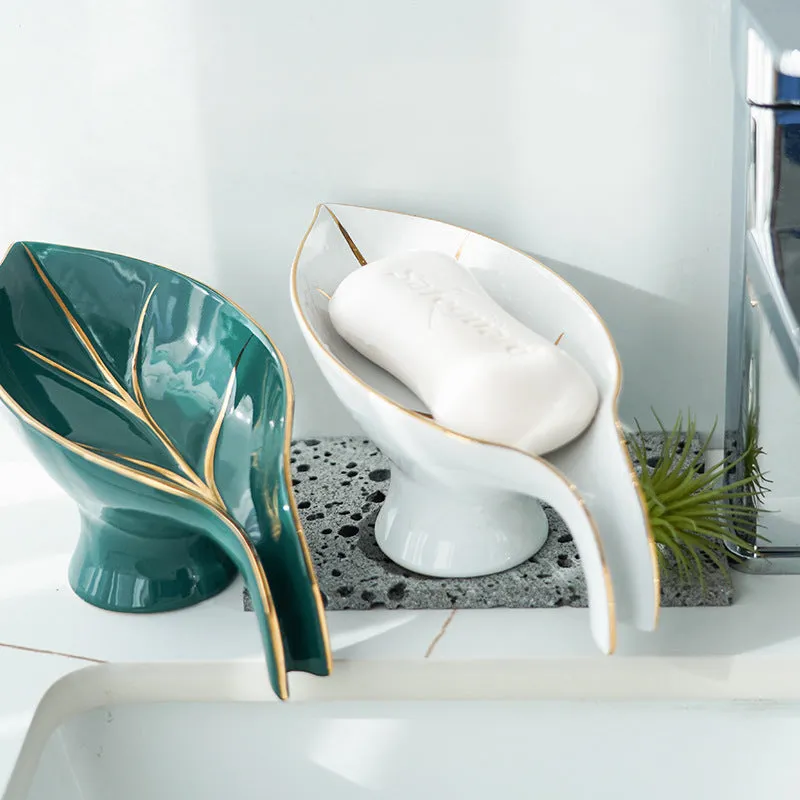 Ceramic leaf shape soap dish with drainage holes and suction cup in white on bathroom counter