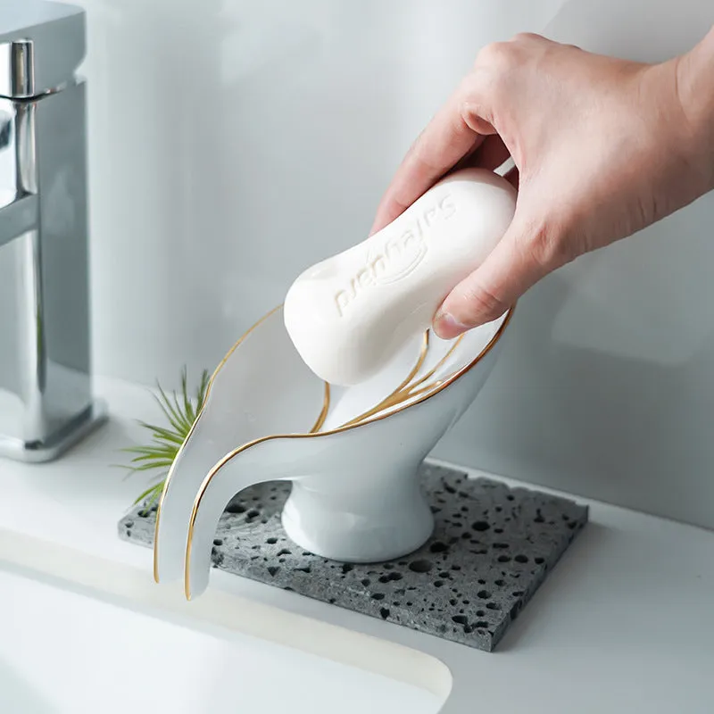 Ceramic leaf shape soap dish with drainage holes and suction cup in white on bathroom counter
