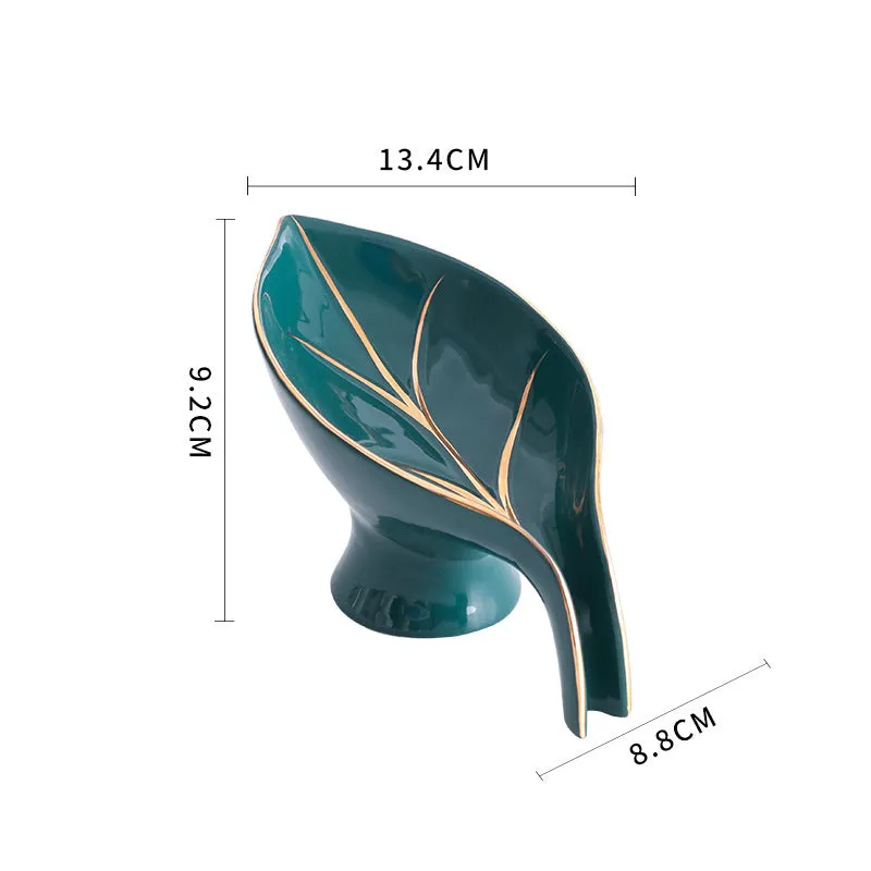Ceramic leaf shape soap dish with drainage holes and suction cup in white on bathroom counter