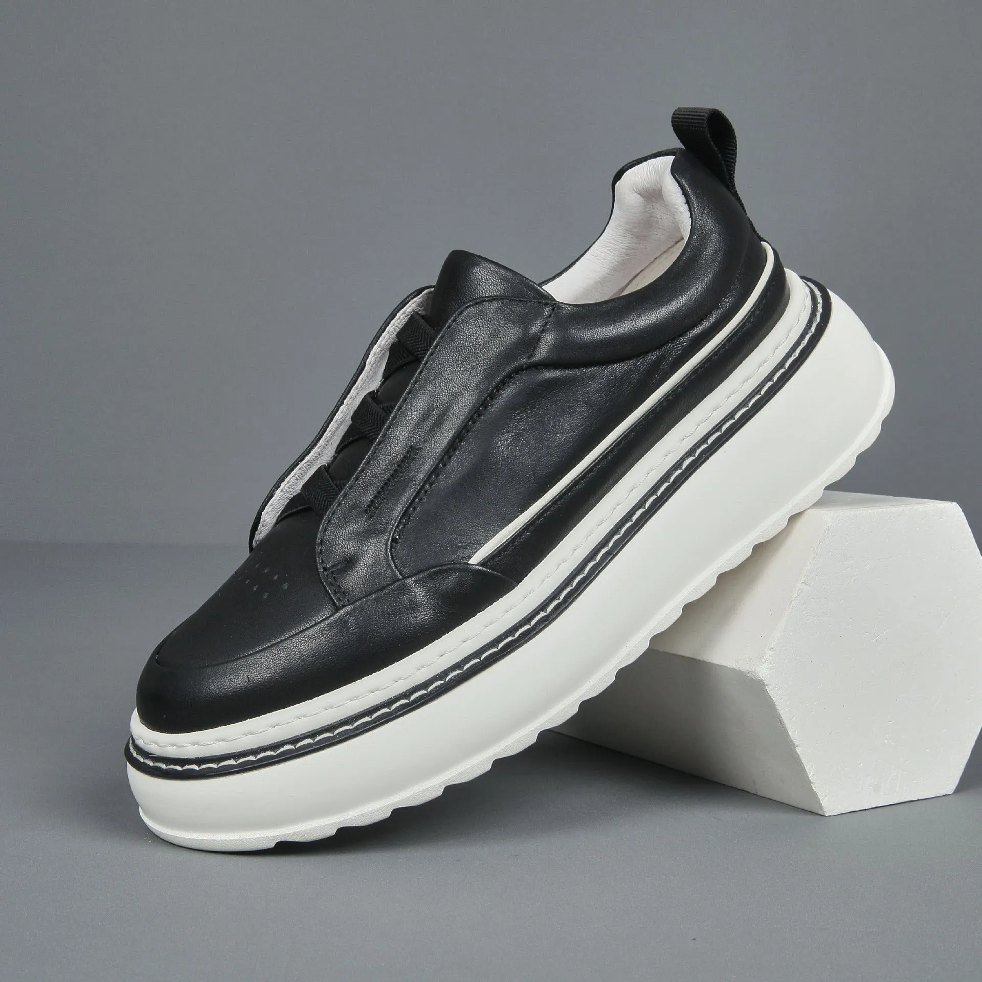 Black casual slip-on sneaker with leather upper, foam platform sole, and elastic band – side view