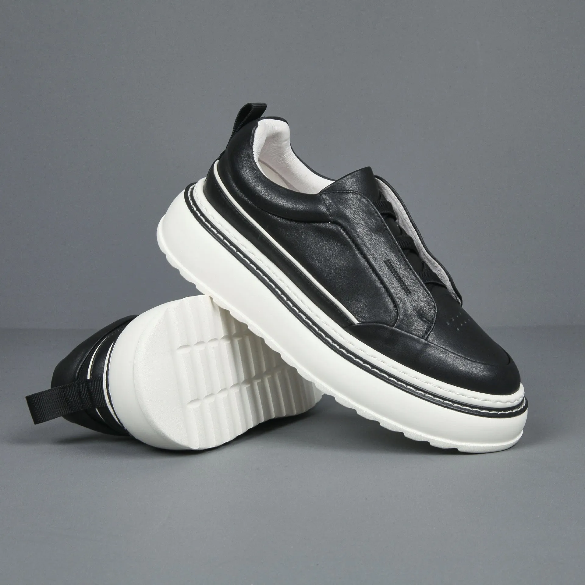 Black casual slip-on sneaker with leather upper, foam platform sole, and elastic band – side view