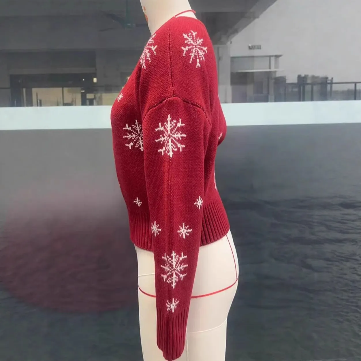 Women's red snowflake jacquard boat neck pullover sweater with long sleeves and crocheted flower details on a white background
