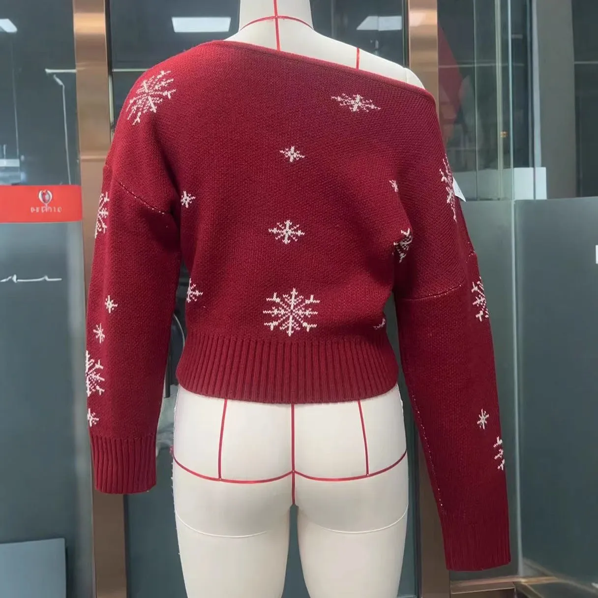 Women's red snowflake jacquard boat neck pullover sweater with long sleeves and crocheted flower details on a white background