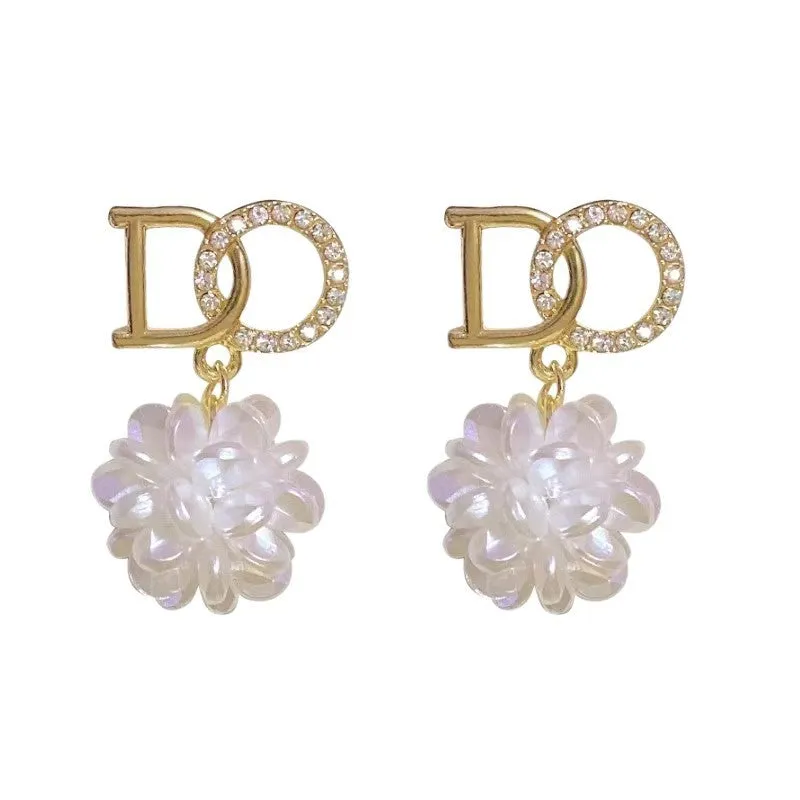 White acrylic DO letter embroidered ball stud earrings for women on light background