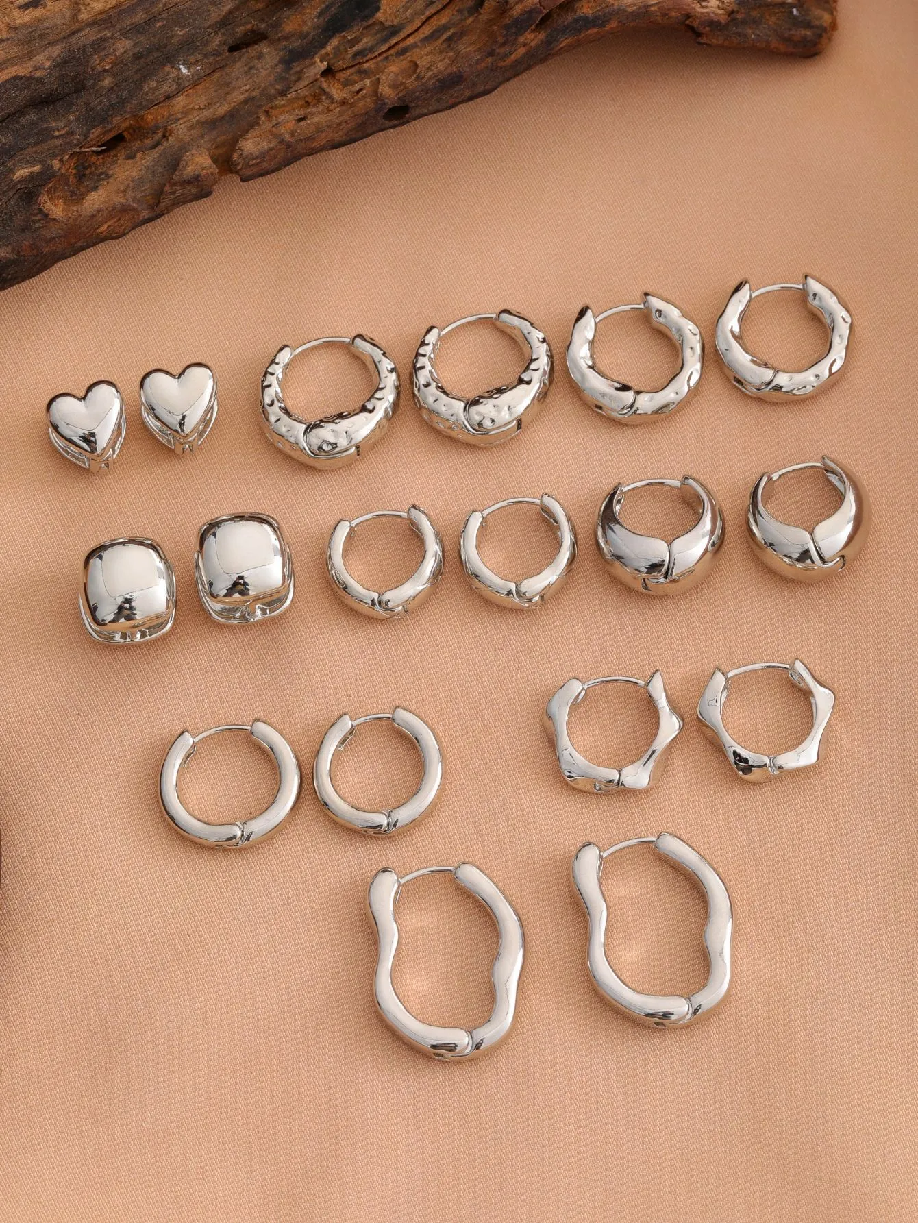 Smooth geometric hollow stud earrings in gold and silver colour options on a neutral background
