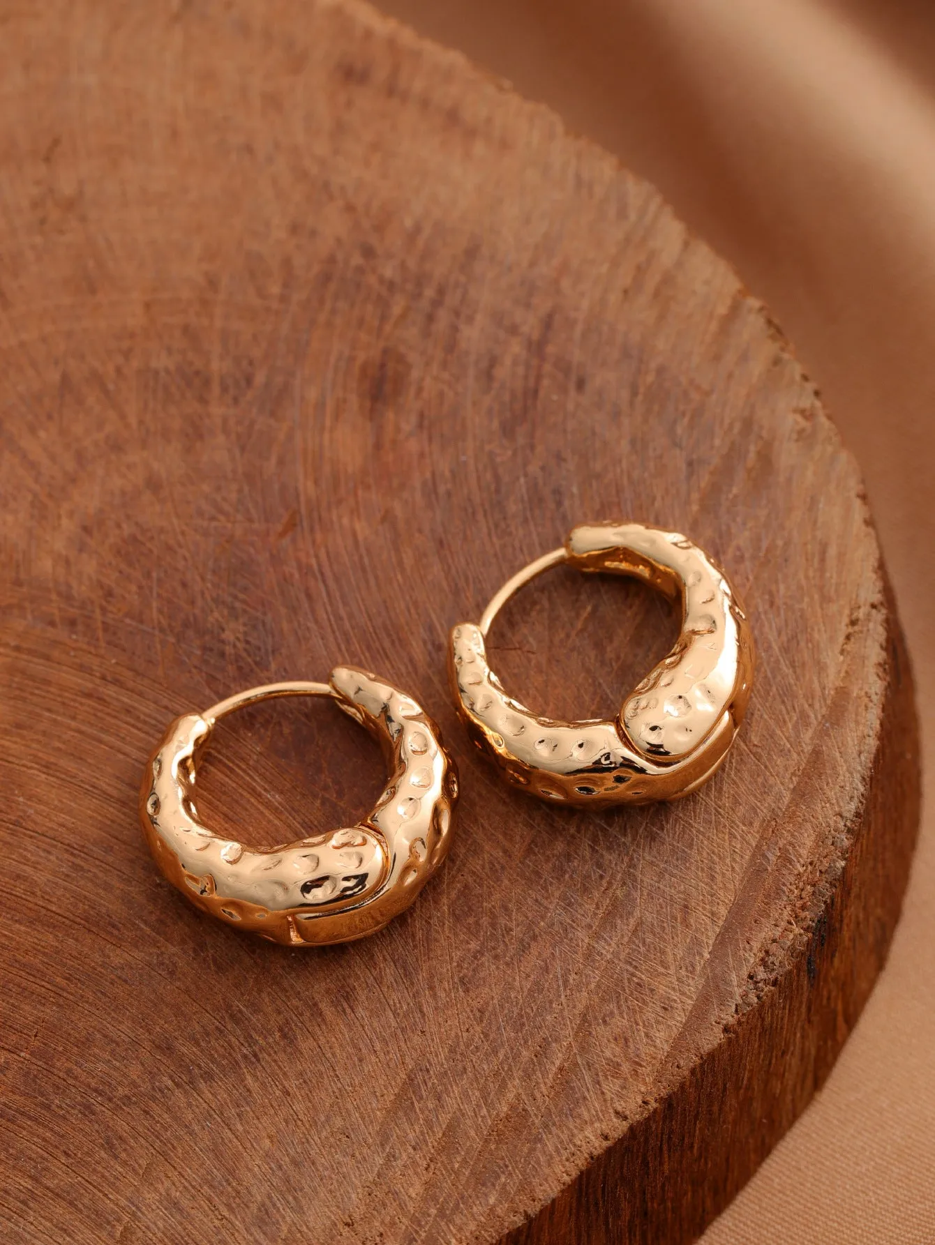 Smooth geometric hollow stud earrings in gold and silver colour options on a neutral background
