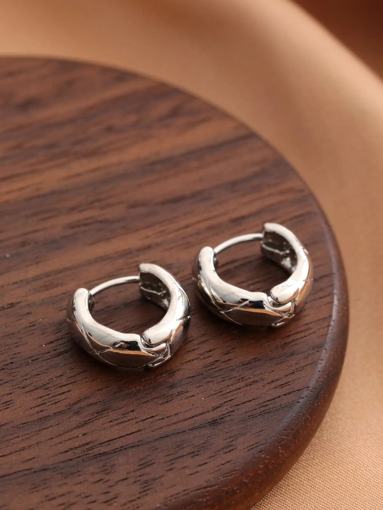 Smooth geometric hollow stud earrings in gold and silver colour options on a neutral background
