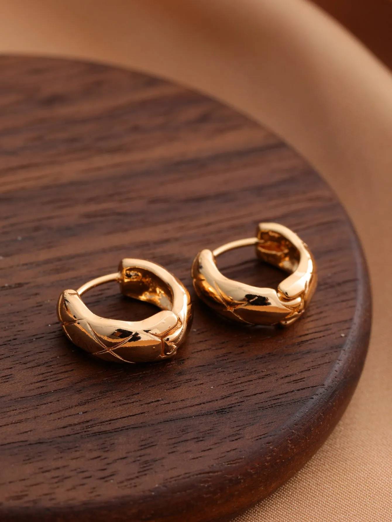 Smooth geometric hollow stud earrings in gold and silver colour options on a neutral background