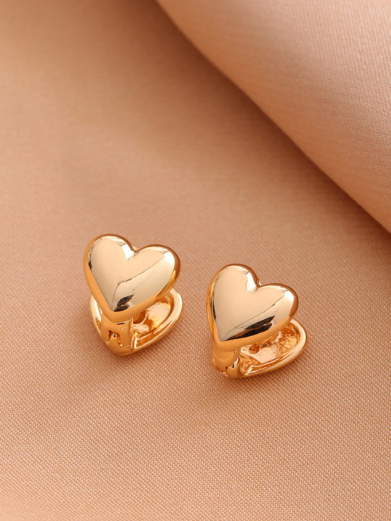 Smooth geometric hollow stud earrings in gold and silver colour options on a neutral background