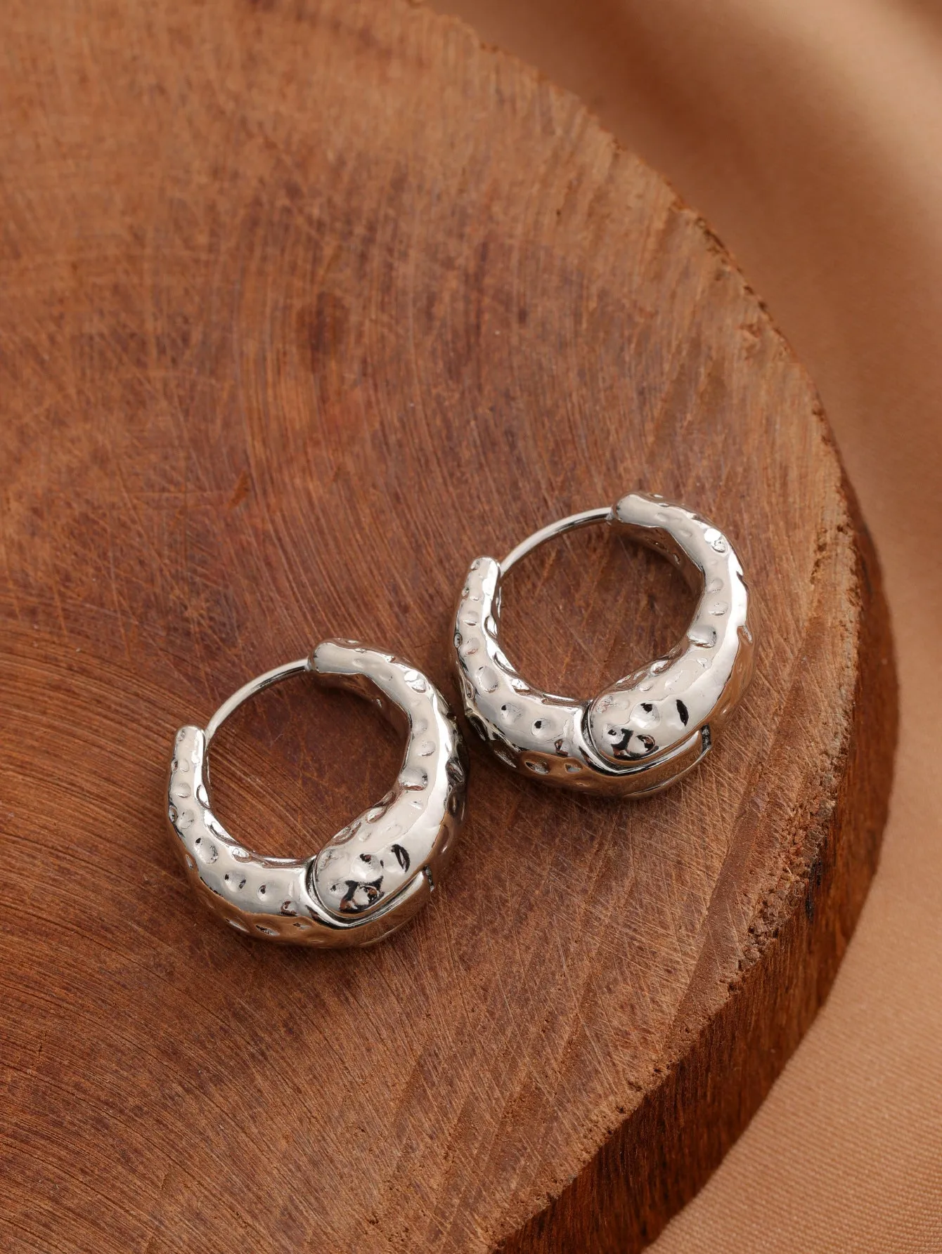 Smooth geometric hollow stud earrings in gold and silver colour options on a neutral background