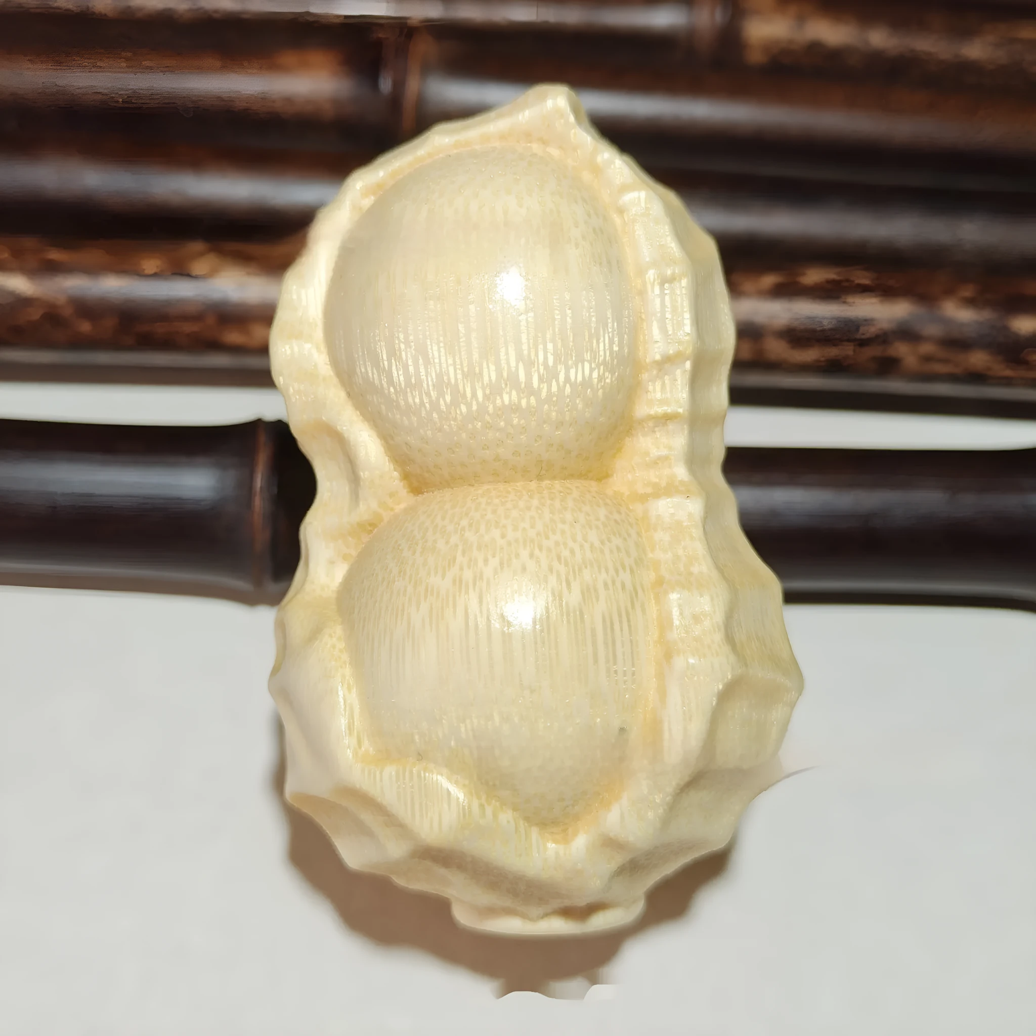 Solid natural bamboo carving of a peanut ornament on a wooden surface