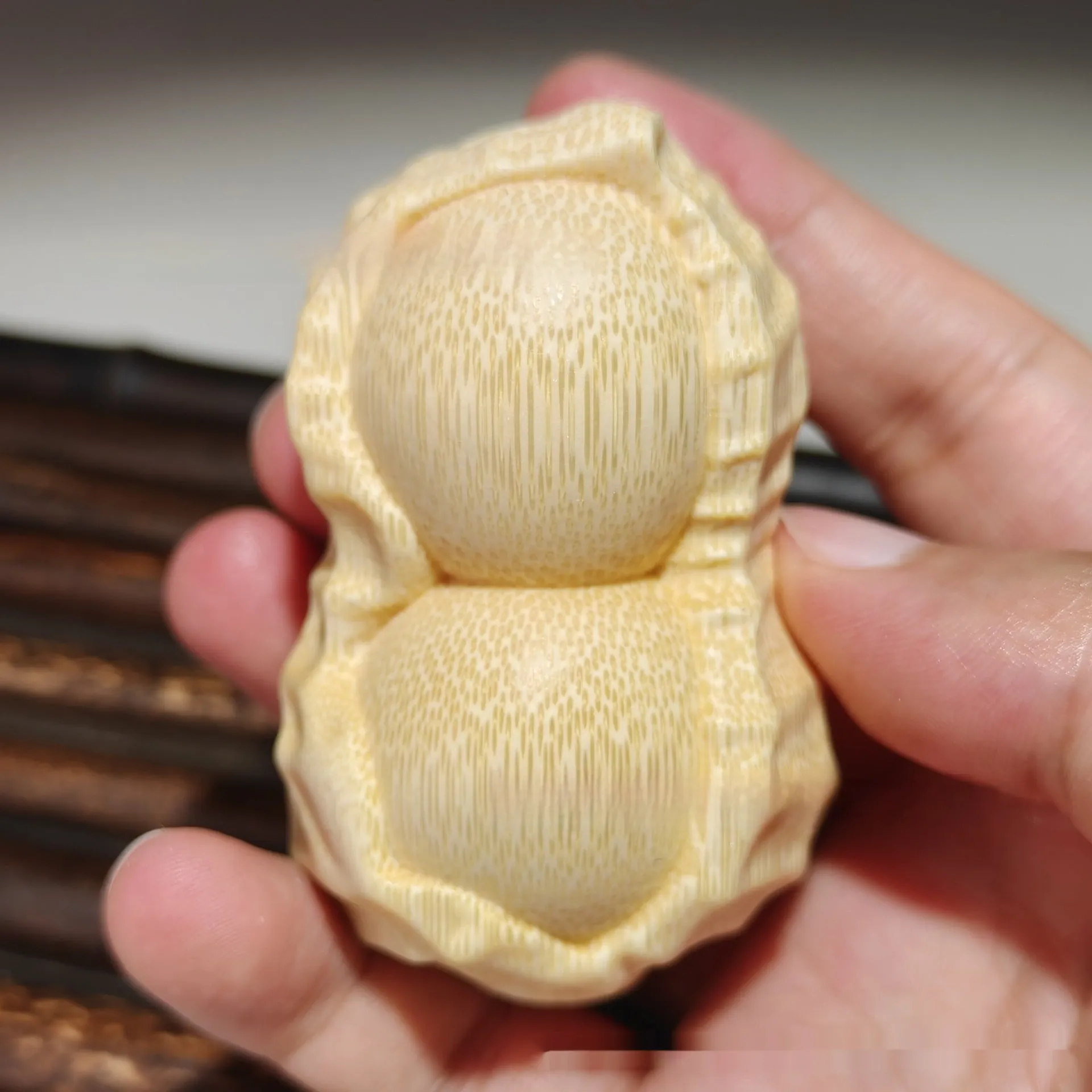Solid natural bamboo carving of a peanut ornament on a wooden surface