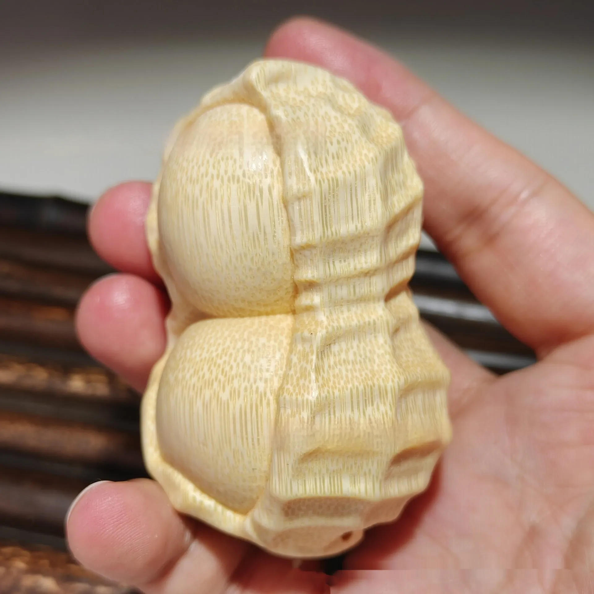 Solid natural bamboo carving of a peanut ornament on a wooden surface