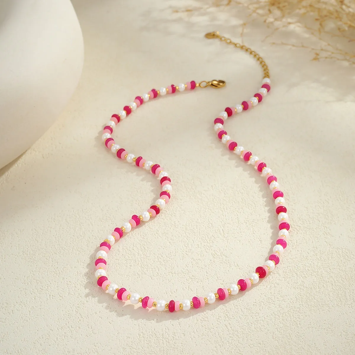 Sweet resin beaded necklace with geometric 18K stainless steel pendant, pink beads, and regular chain on light background