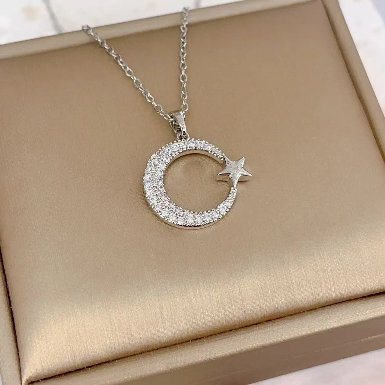 Xingyue gold geometric moon pendant necklace with zircon stone on titanium steel O-ring chain against white background