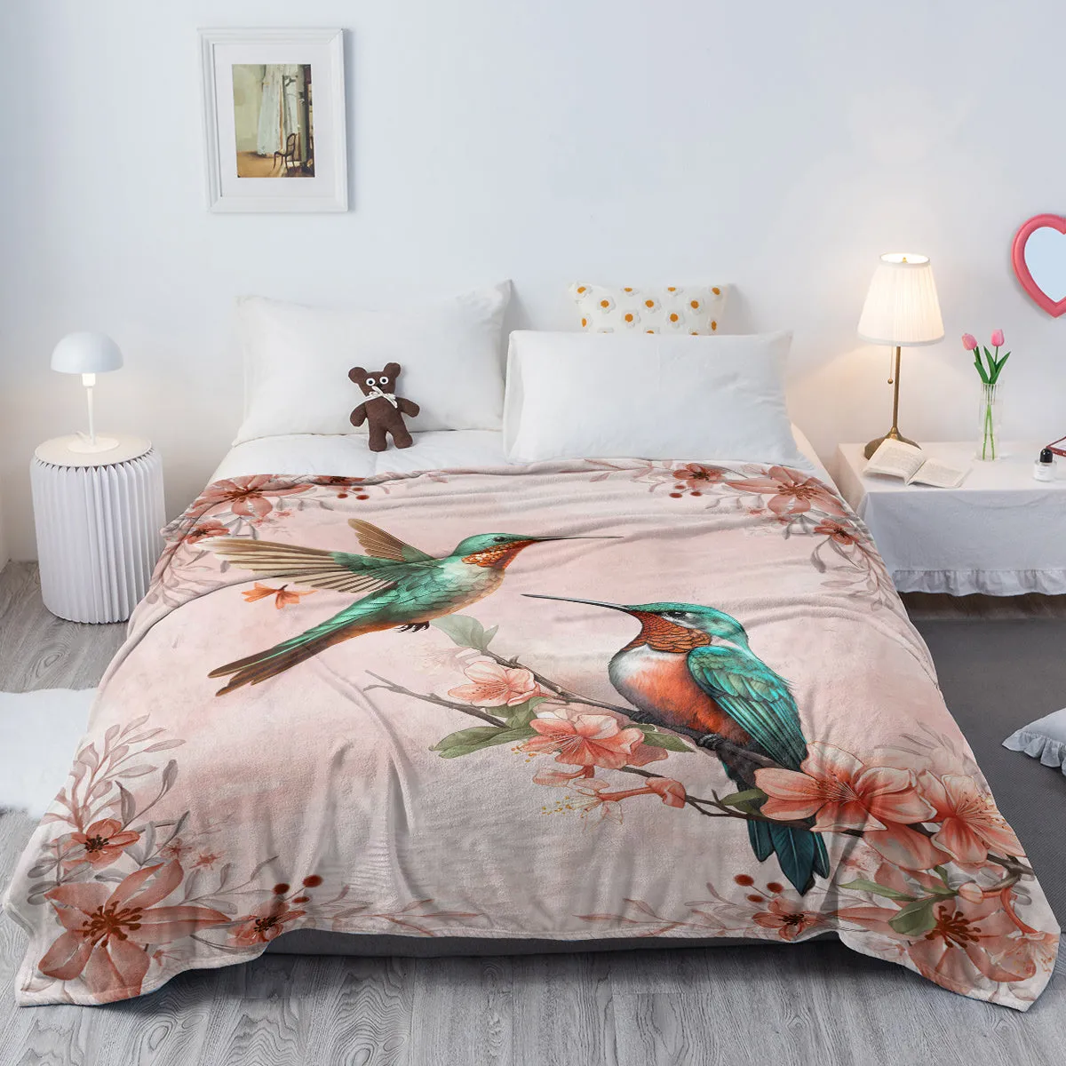 Pink hummingbird floral fleece throw blanket made of soft flannel velvet, folded on a sofa