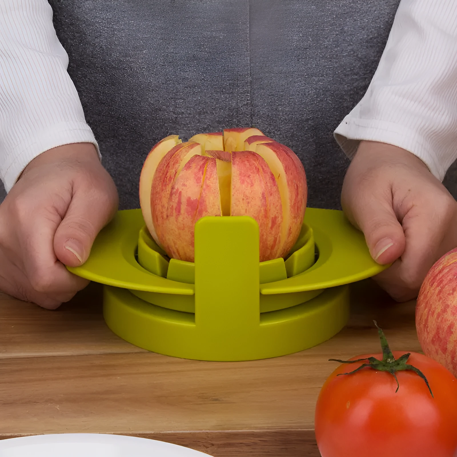 Green fruit slicer with three cutting sections for apple, tomato, and mango on a base
