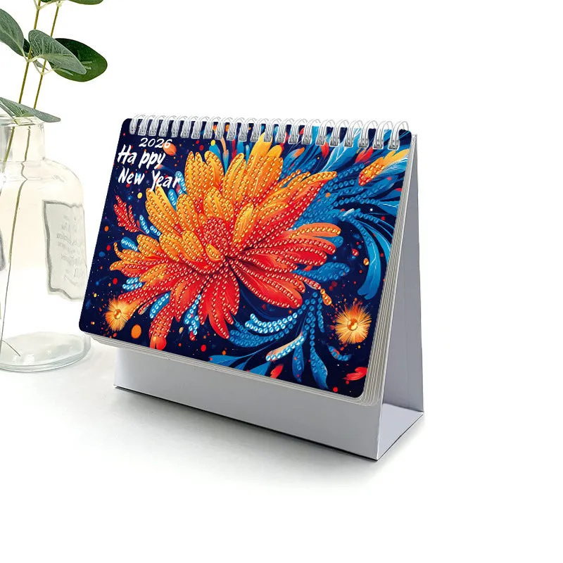 Frameless white card desk calendar with cartoon diamond painting design and stick-on crystals on a desk surface.