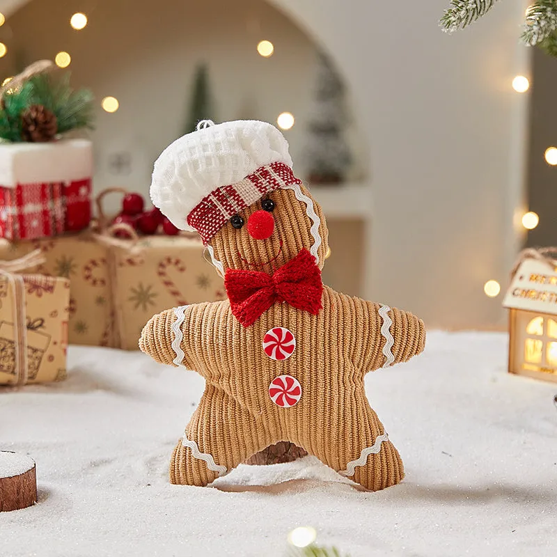 Cloth gingerbread man Christmas ornament with red hat hanging on festive branch
