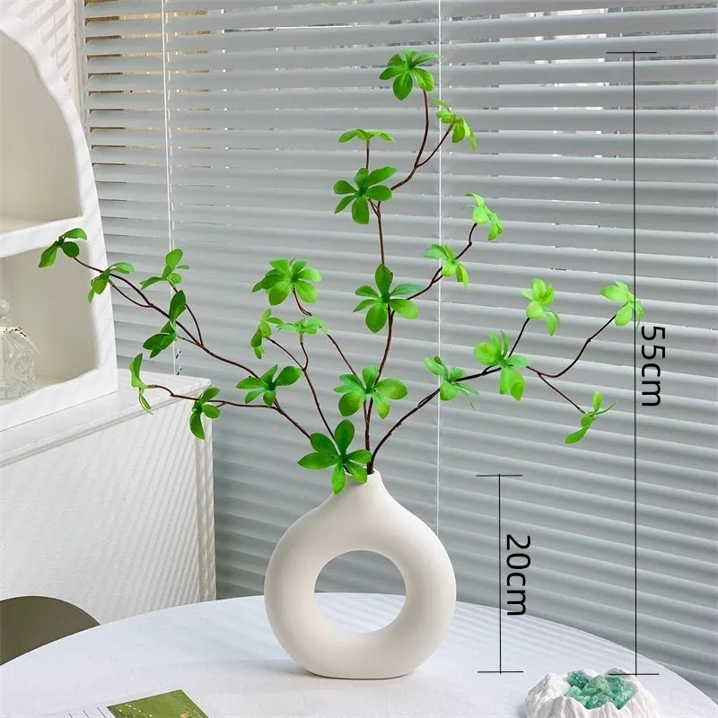 Artificial silk flower arrangement in a glass bottle vase, suitable for indoor home decor on a table