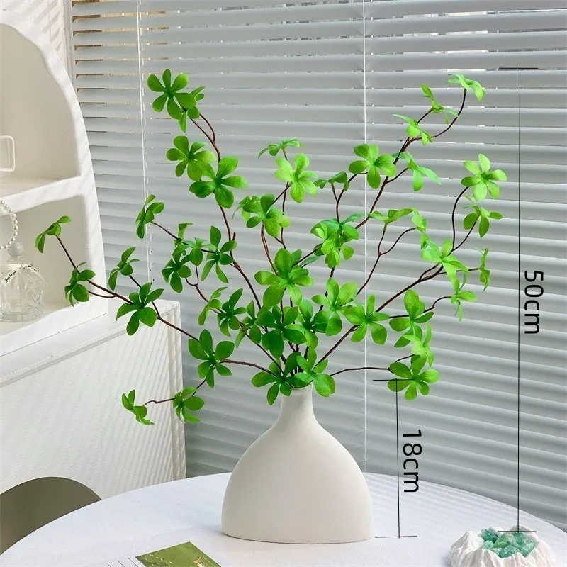 Artificial silk flower arrangement in a glass bottle vase, suitable for indoor home decor on a table