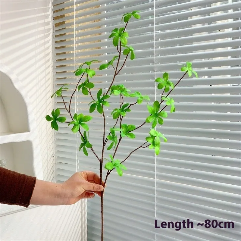 Artificial silk flower arrangement in a glass bottle vase, suitable for indoor home decor on a table