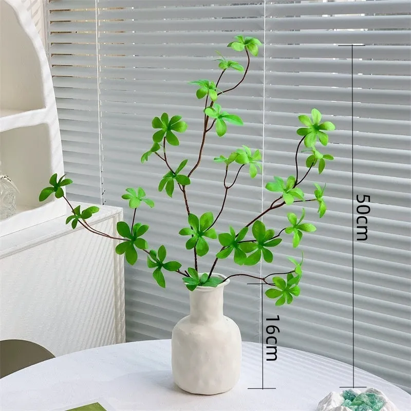 Artificial silk flower arrangement in a glass bottle vase, suitable for indoor home decor on a table