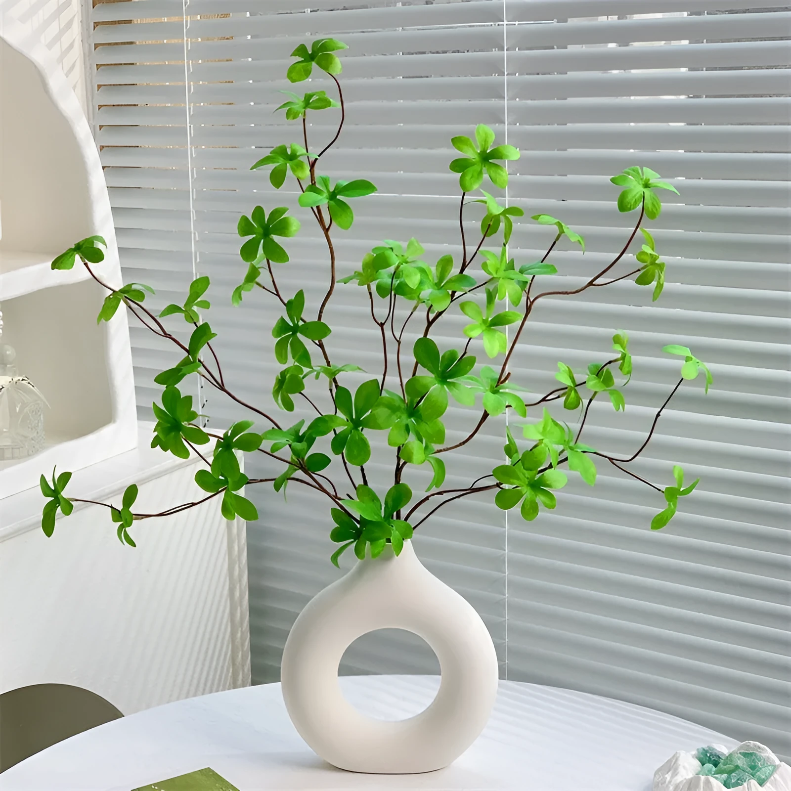 Artificial silk flower arrangement in a glass bottle vase, suitable for indoor home decor on a table