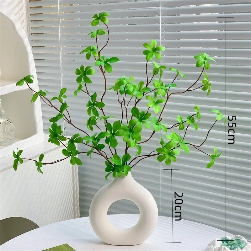 Artificial silk flower arrangement in a glass bottle vase, suitable for indoor home decor on a table