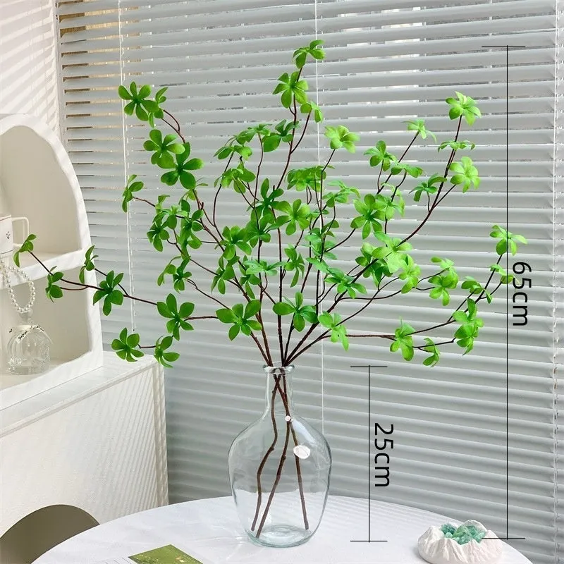 Artificial silk flower arrangement in a glass bottle vase, suitable for indoor home decor on a table