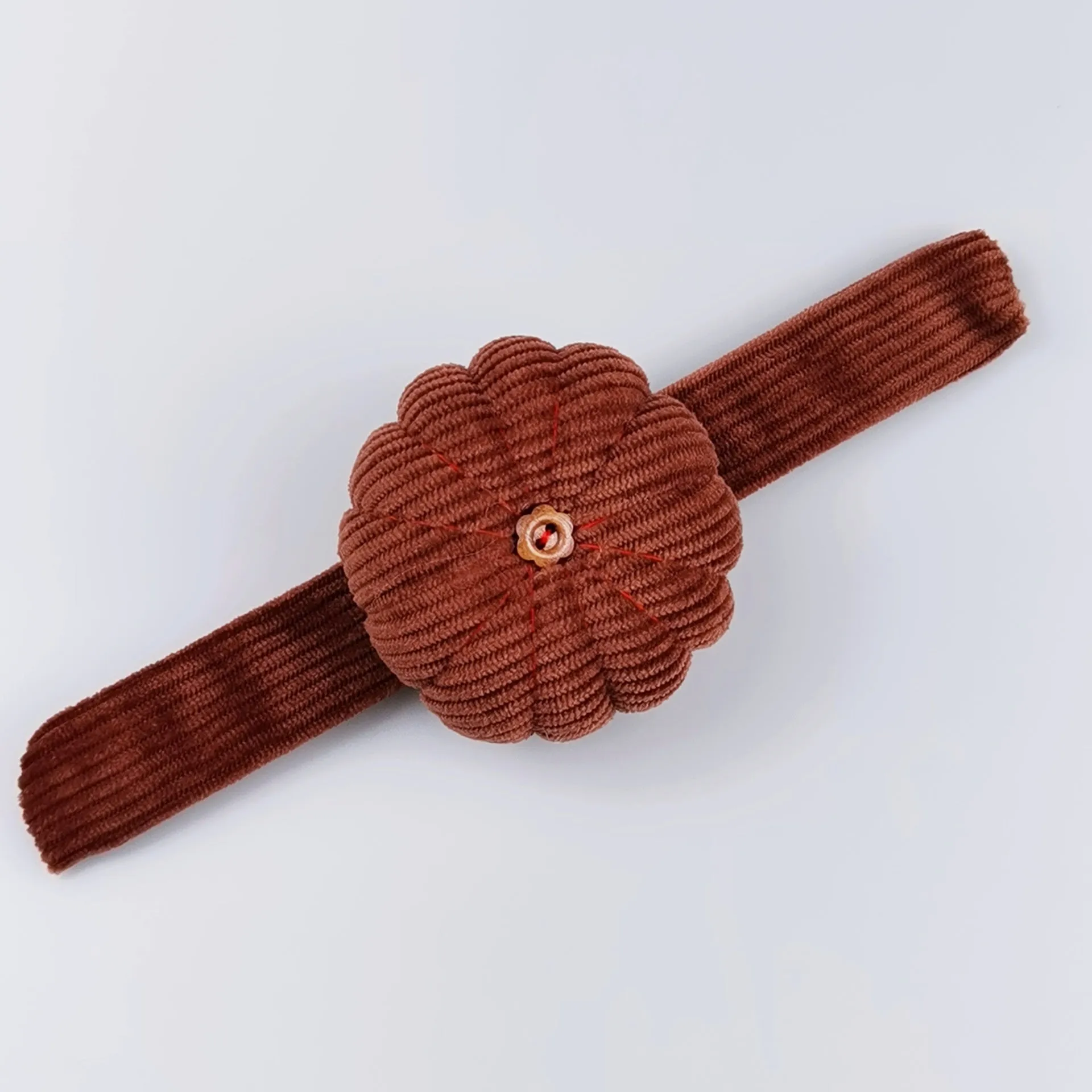 Ring pincushion sewing tool with vertical cutting slot in caramel colour showing fabric cushion and metal ring base