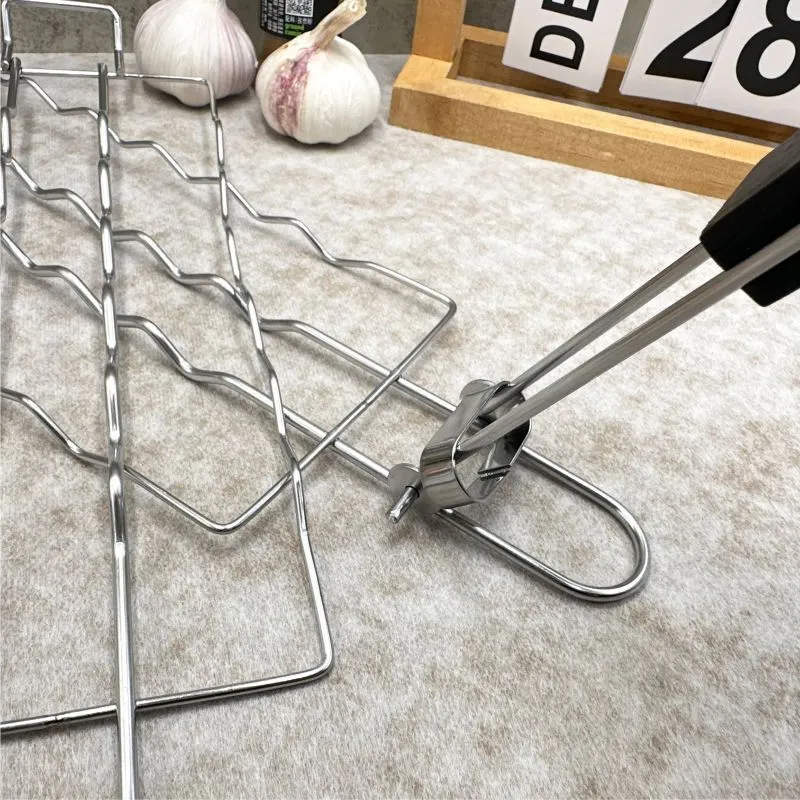 Stainless steel removable folding outdoor barbecue net, square modern style, with black handle, placed over charcoal fire.