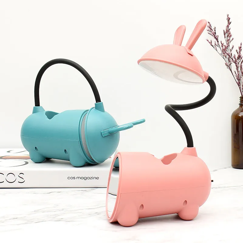 Cartoon-style USB table lamp with integrated pen container in green colour on wooden desk