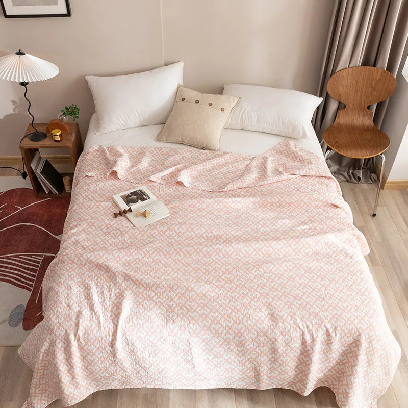 Pure cotton washed cover blanket with geometric pattern in glini pink, folded on a bed