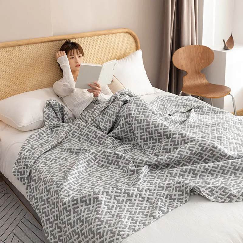 Pure cotton washed cover blanket with geometric pattern in glini pink, folded on a bed