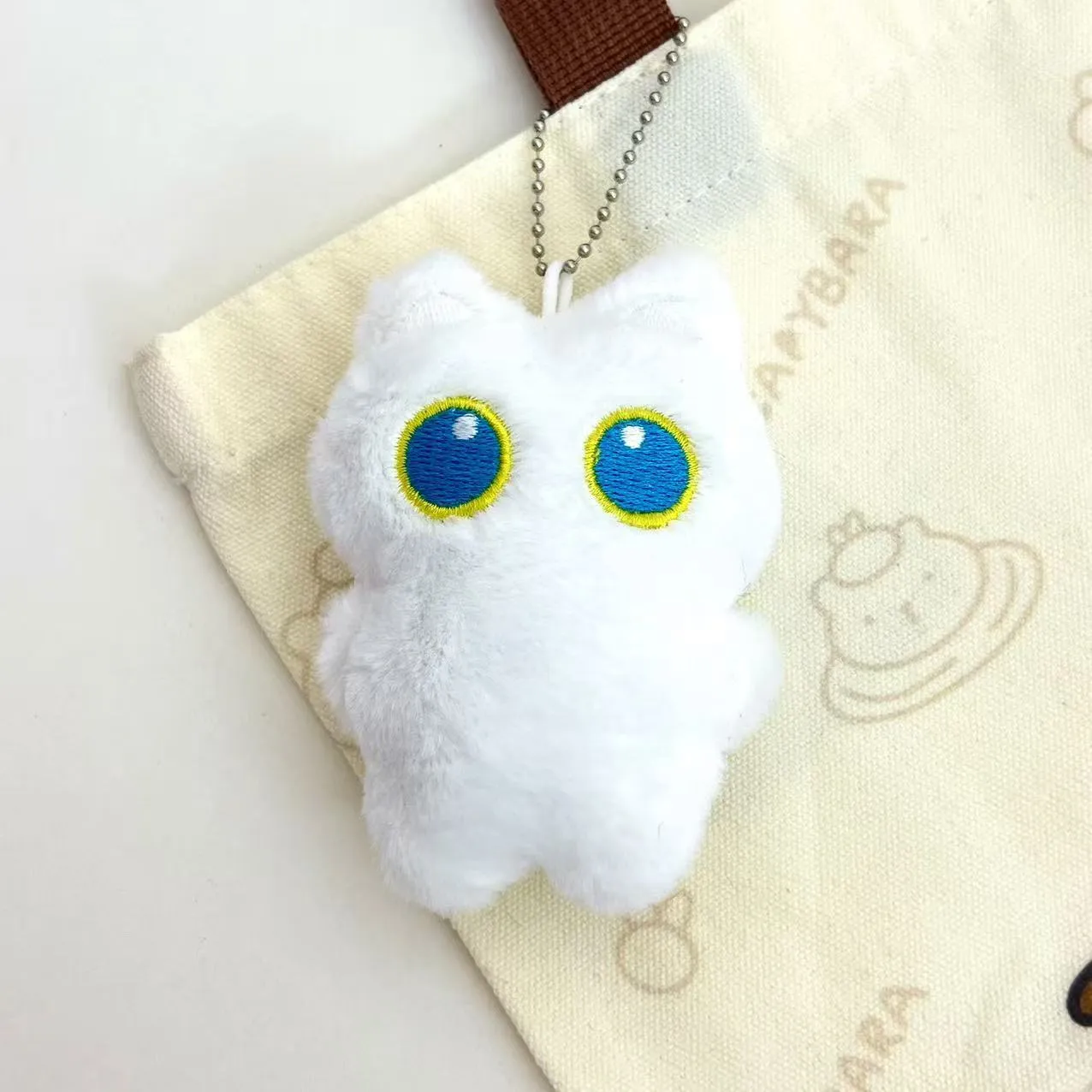 Cartoon big eye black cat doll plush with bead necklace as key decoration on a bag