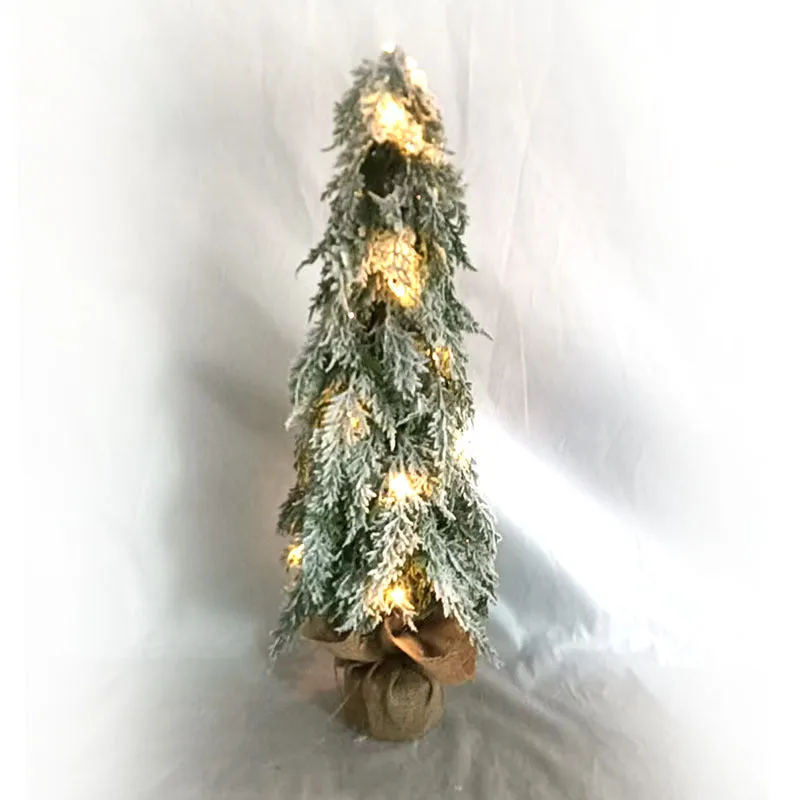 Small 24-inch white artificial Christmas tree with lights and snow spray on a desktop