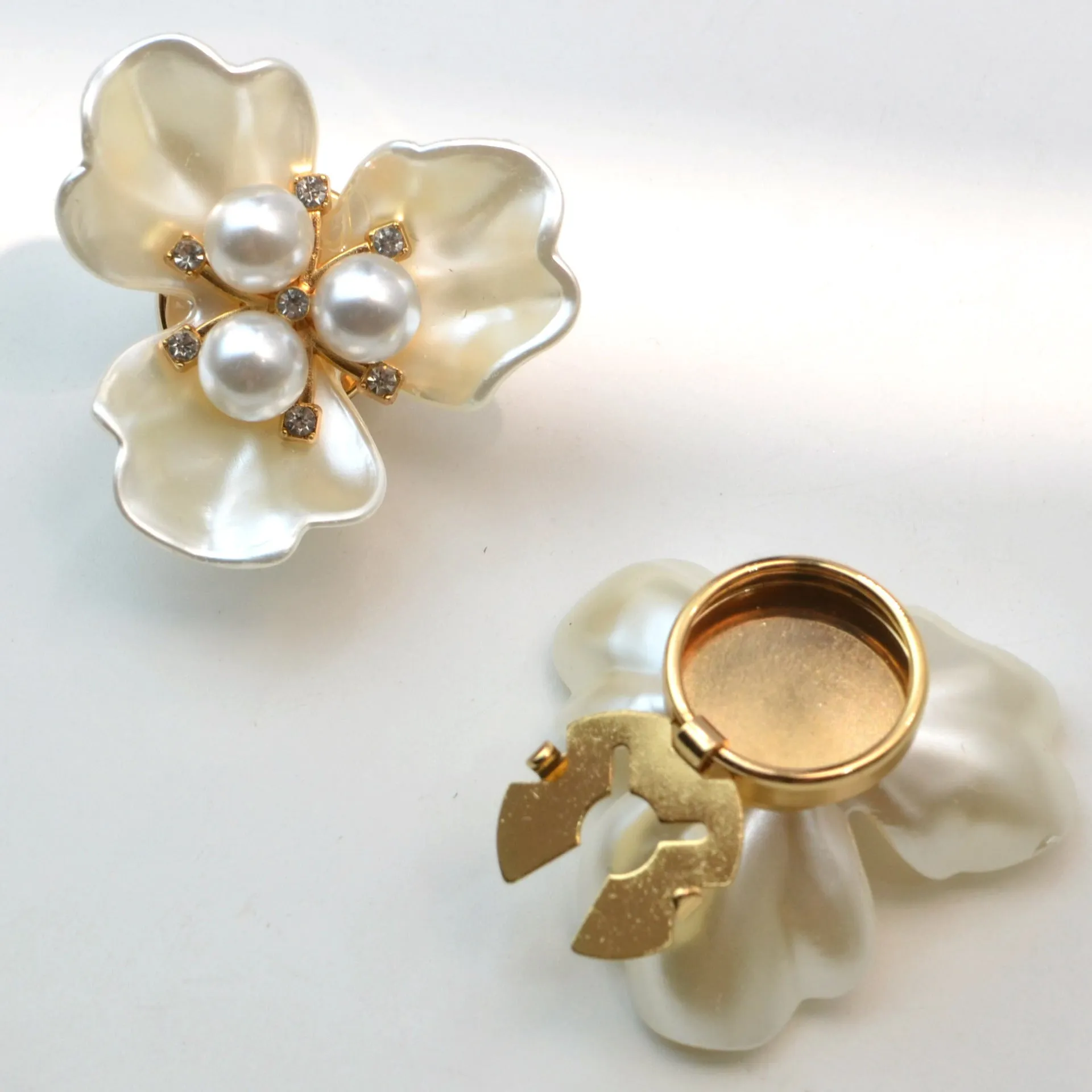 Metal cufflinks with pearl three-flap design in gold, pink, red, and white colours on white background