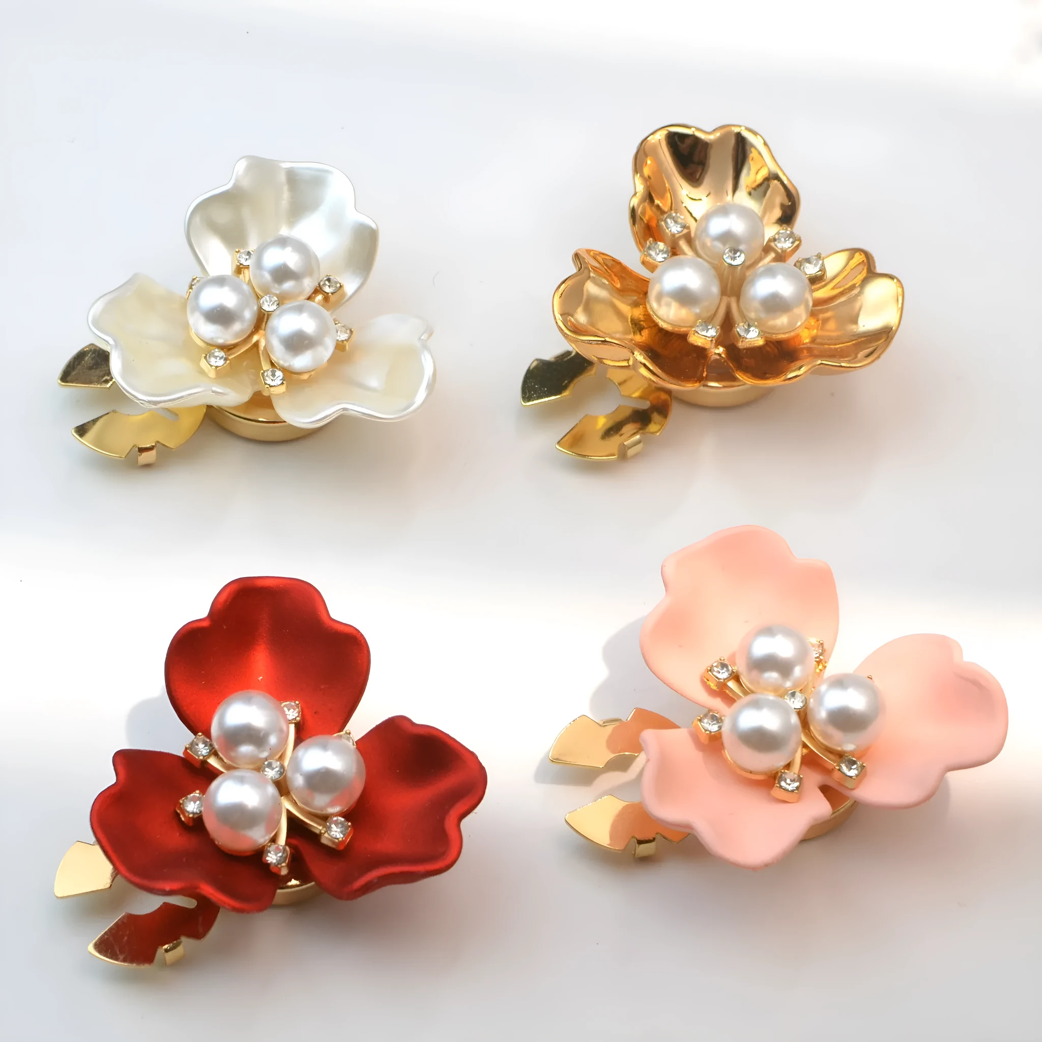Metal cufflinks with pearl three-flap design in gold, pink, red, and white colours on white background