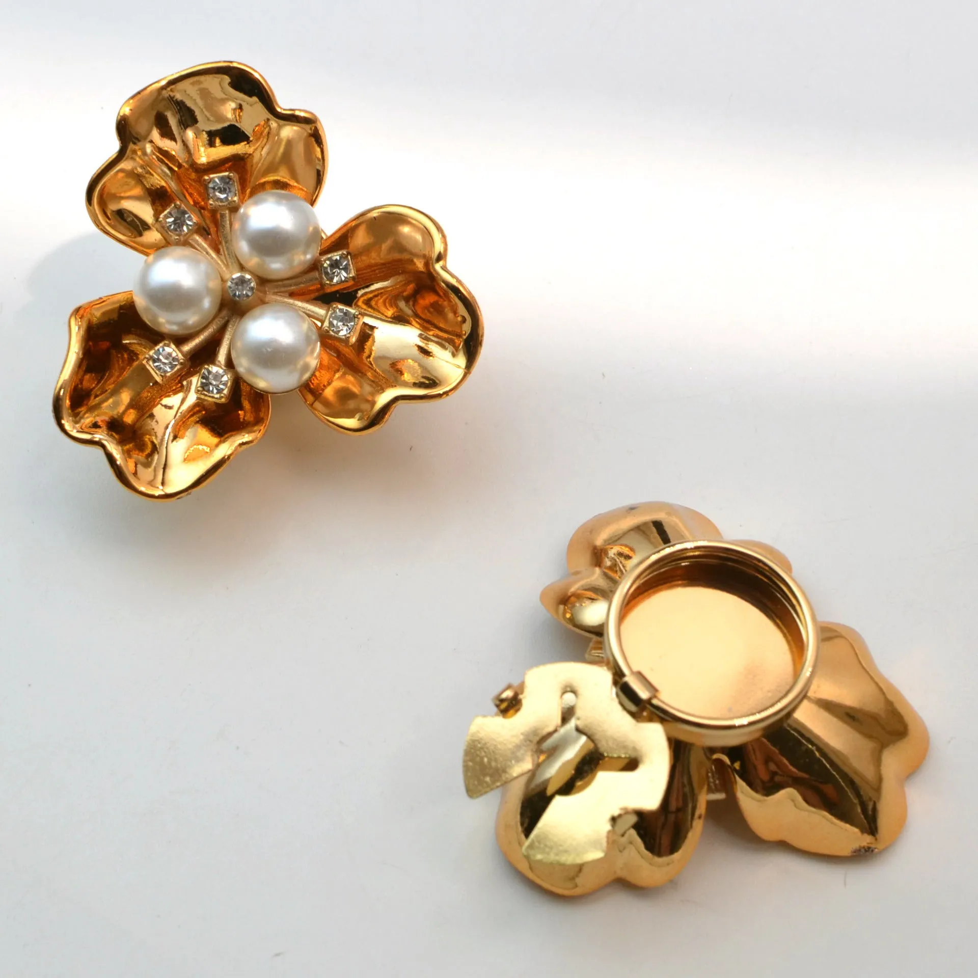 Metal cufflinks with pearl three-flap design in gold, pink, red, and white colours on white background
