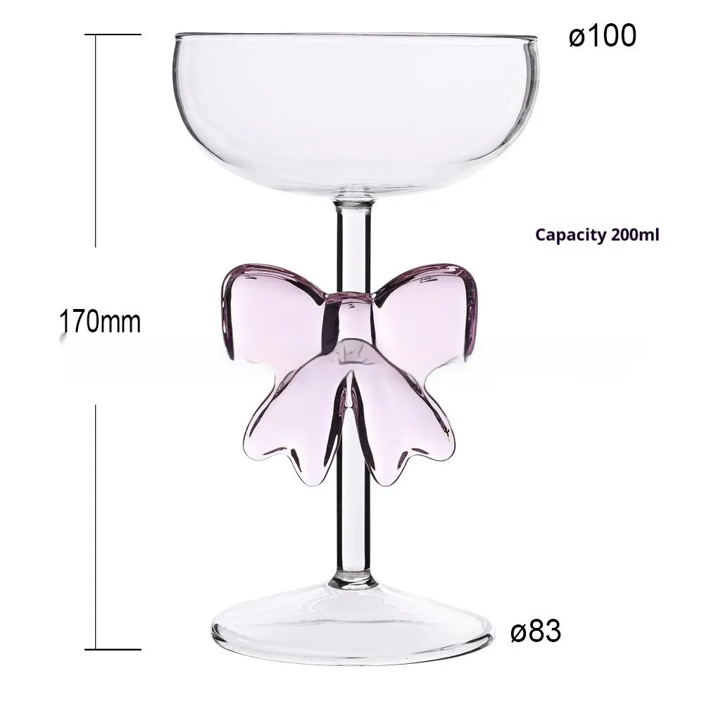 Set of three clear borosilicate glass candlesticks with large bow decorations on a table